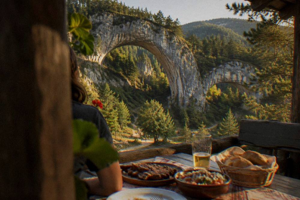 A rustic restaurant table with grilled meat, salad and bread in a mountain village