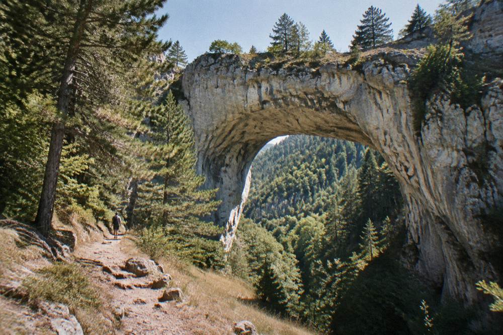 Natural rock arch bridge in a forested Rhodope mountain valley