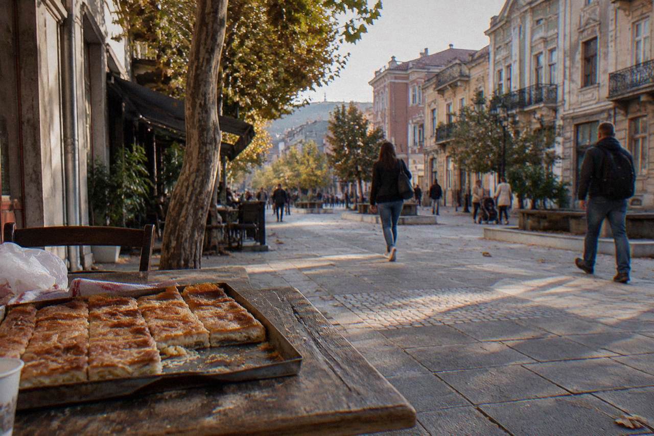 A freshly baked tray of golden banitsa pastry cut into squares on a rustic table