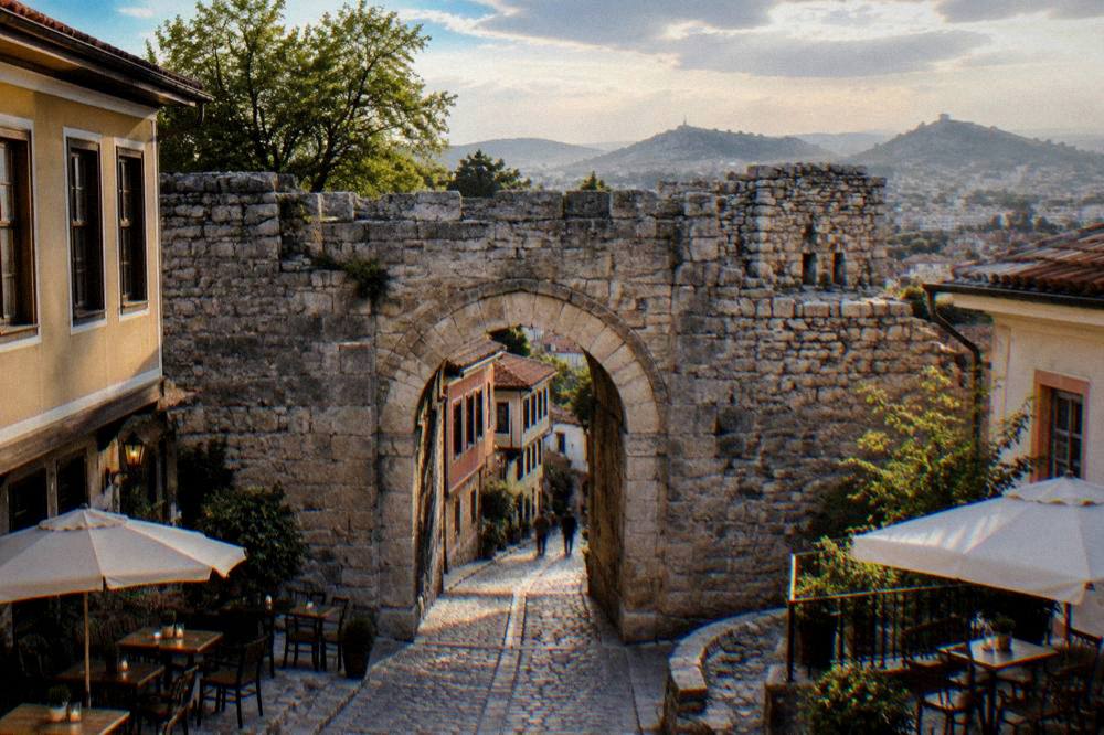 The stone gate of Hisar Kapia in Plovdiv with small tables and chairs of nearby eateries in the evening