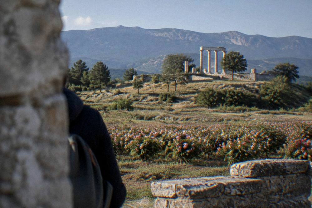 A stone Thracian temple complex with columns on a green hilltop