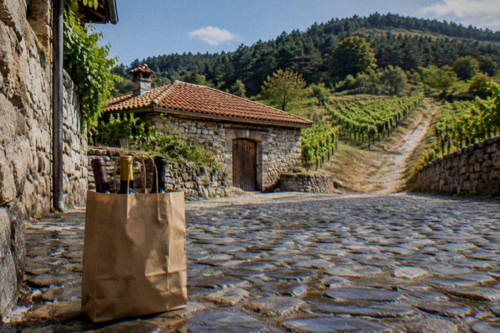A shopping bag with wine bottles standing on a cobblestone street