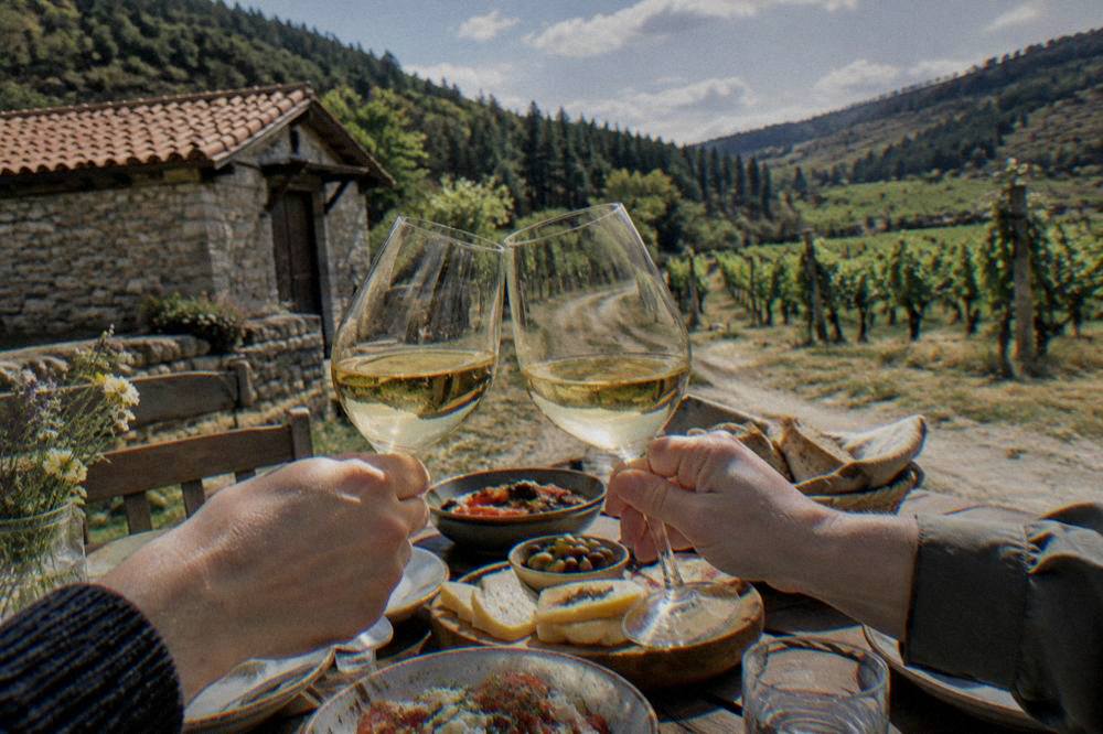 Two full wine glasses raised in a toast above a table of shared dishes