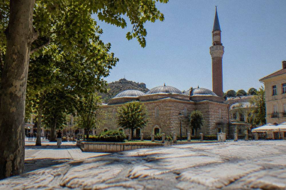 Minaret and brick walls of a historic mosque beside a city square