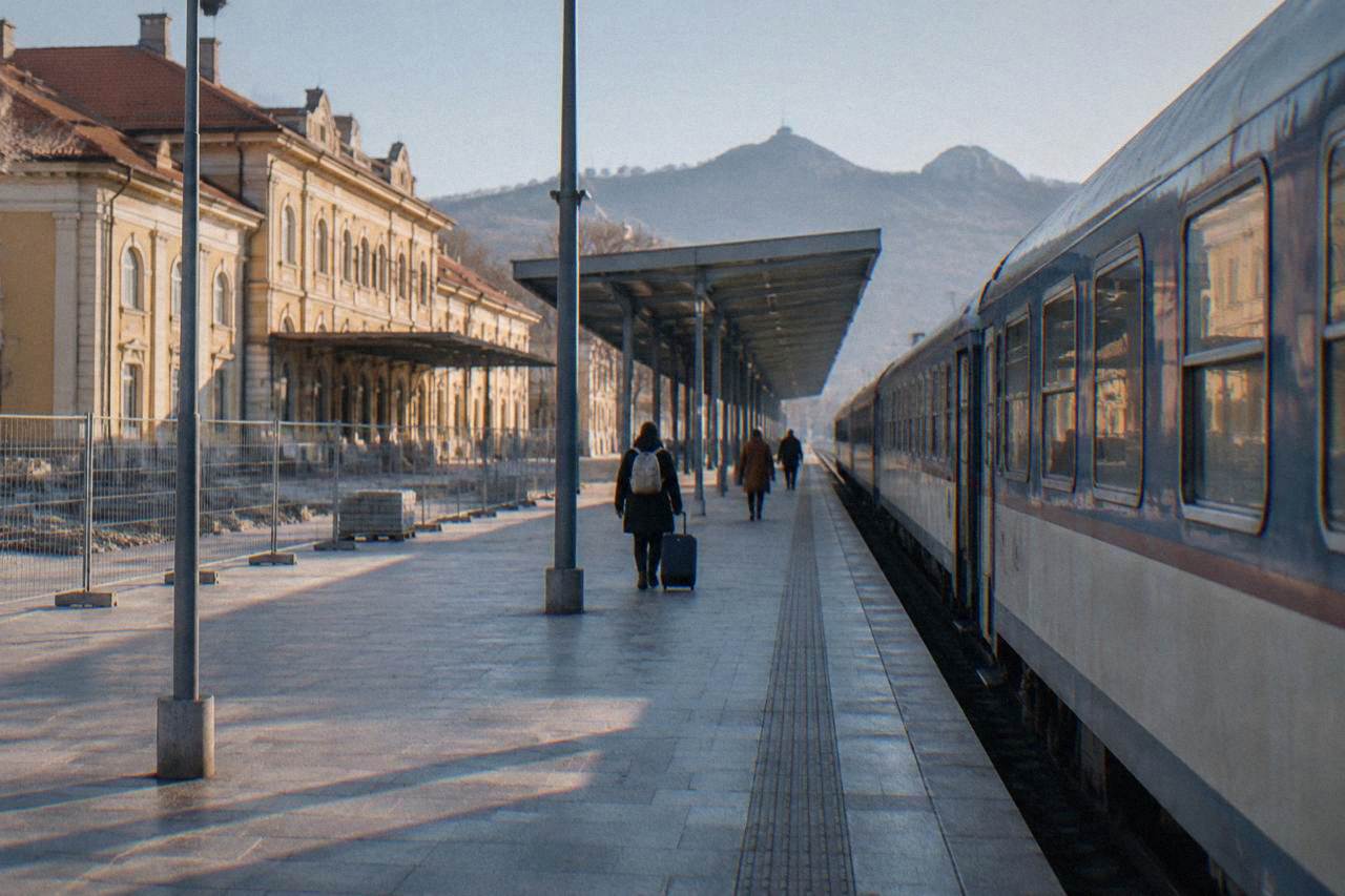 A railway platform in Bulgaria with a passenger train waiting beside the tracks