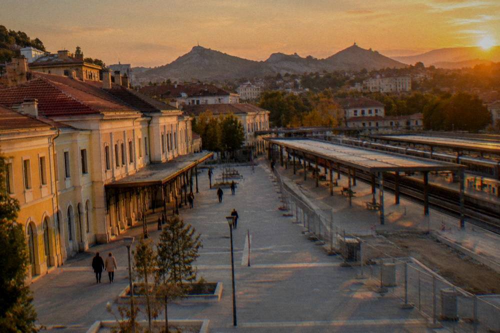 An evening view over a Bulgarian city with lit streets and hills in the background