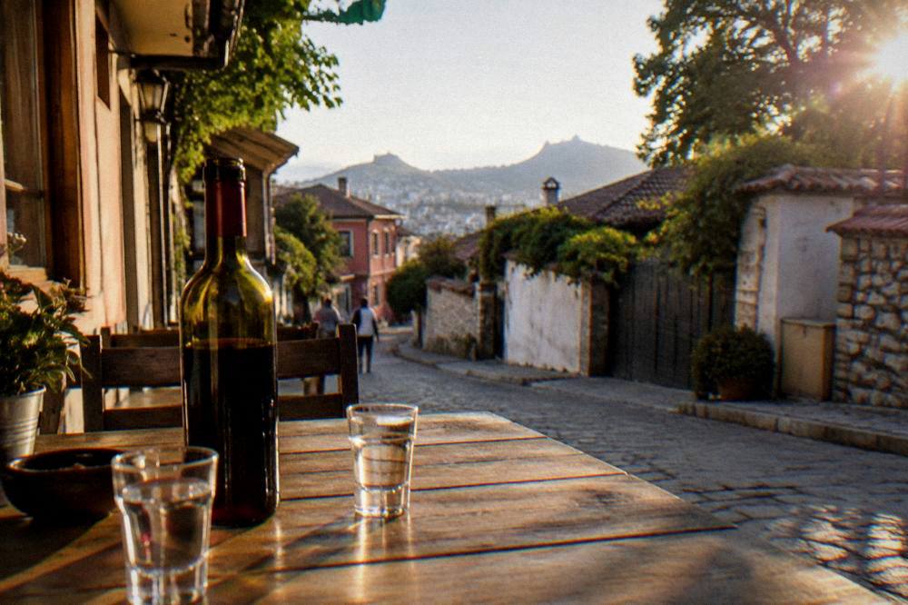 Small glasses of clear fruit brandy and a bottle of red wine standing on a wooden restaurant table