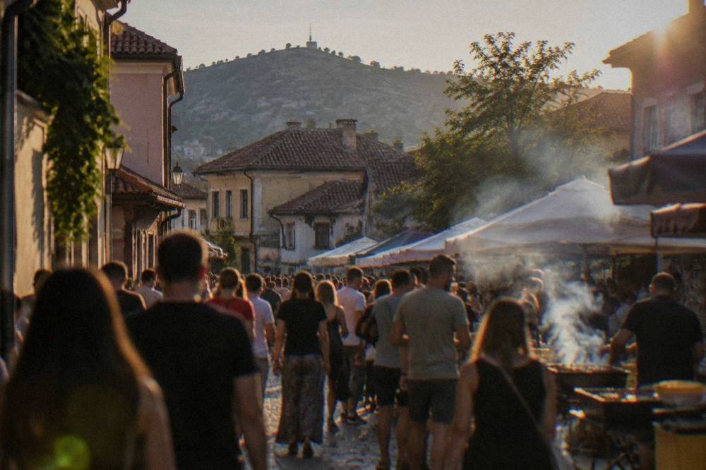 Crowds at an outdoor street festival with food stalls and smoke rising from grills