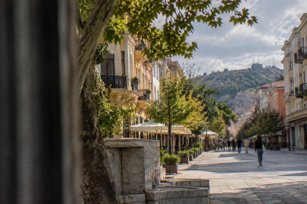 A waiter returning change to a customer at an outdoor restaurant table in Plovdiv