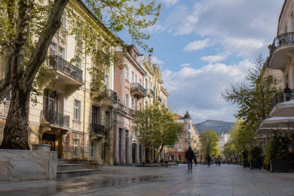 A traveller counting euro coins at a sunny outdoor table in Plovdiv