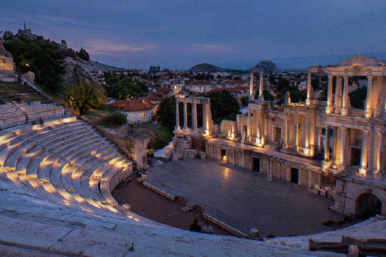 Illuminated marble seating rows of an ancient theatre seen against a dark evening sky
