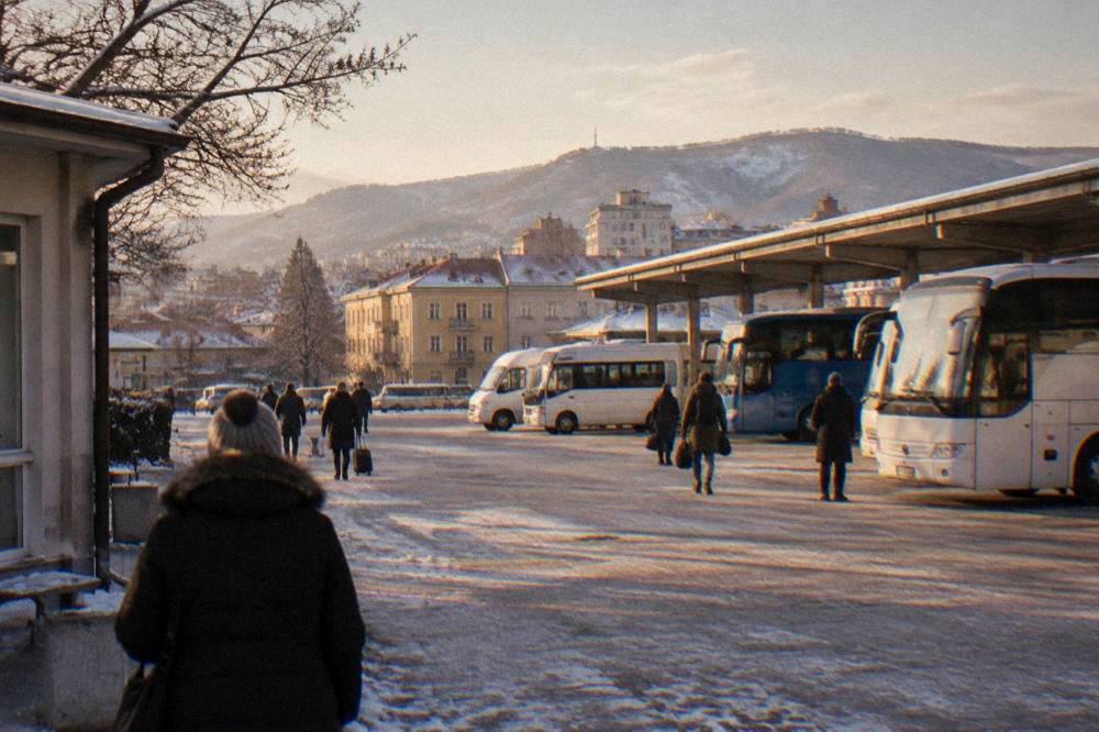 A snowy bus station forecourt in winter with mountains visible in the distance