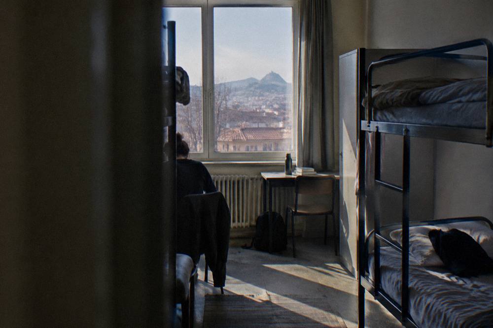 A hostel-style dormitory room with bunk beds and a large window