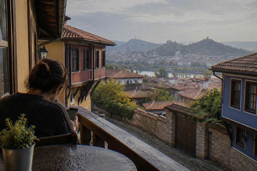 A traveller reading a phone on a balcony overlooking rooftops in central Plovdiv