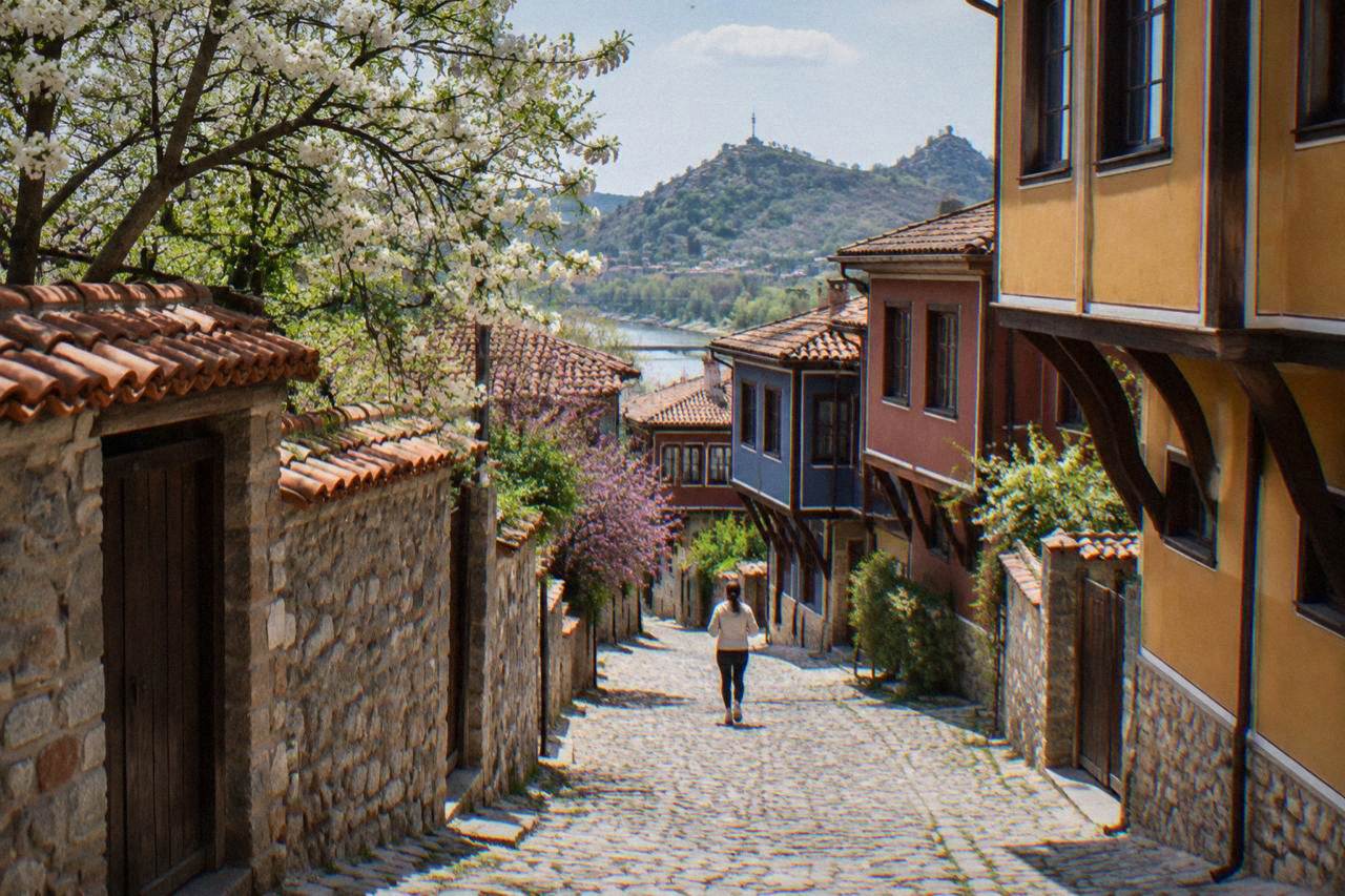 Blossoming trees along a cobbled street in Plovdiv Old Town with colourful revival-era houses