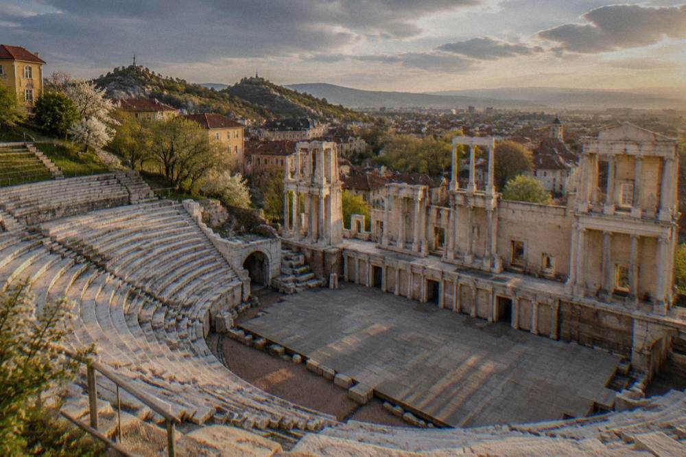 An empty Ancient Theatre stage at golden hour with the city skyline beyond