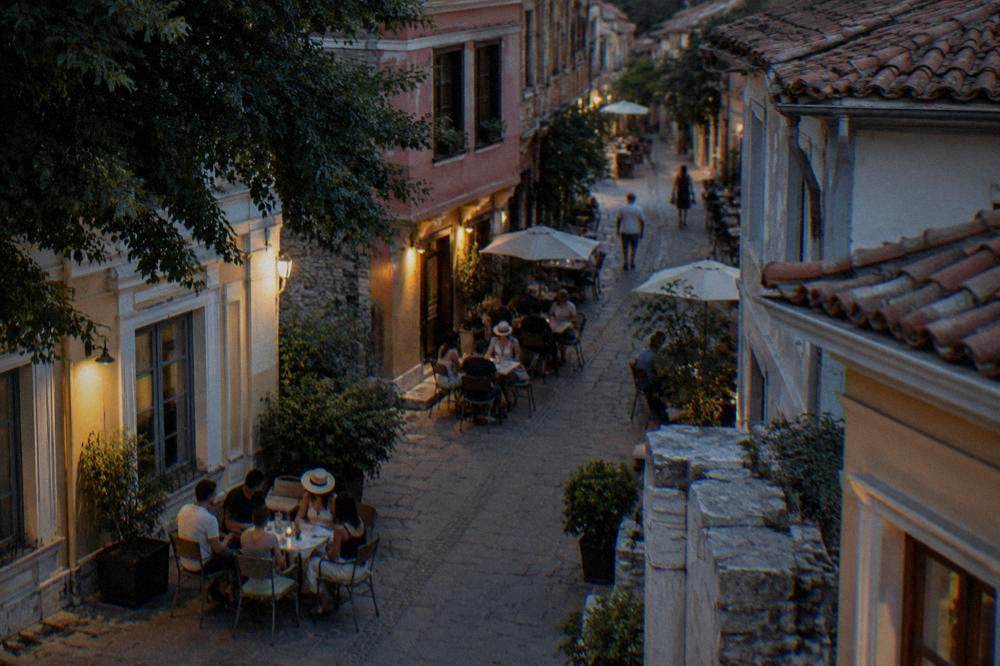 People at outdoor tables in a narrow Kapana street in the evening
