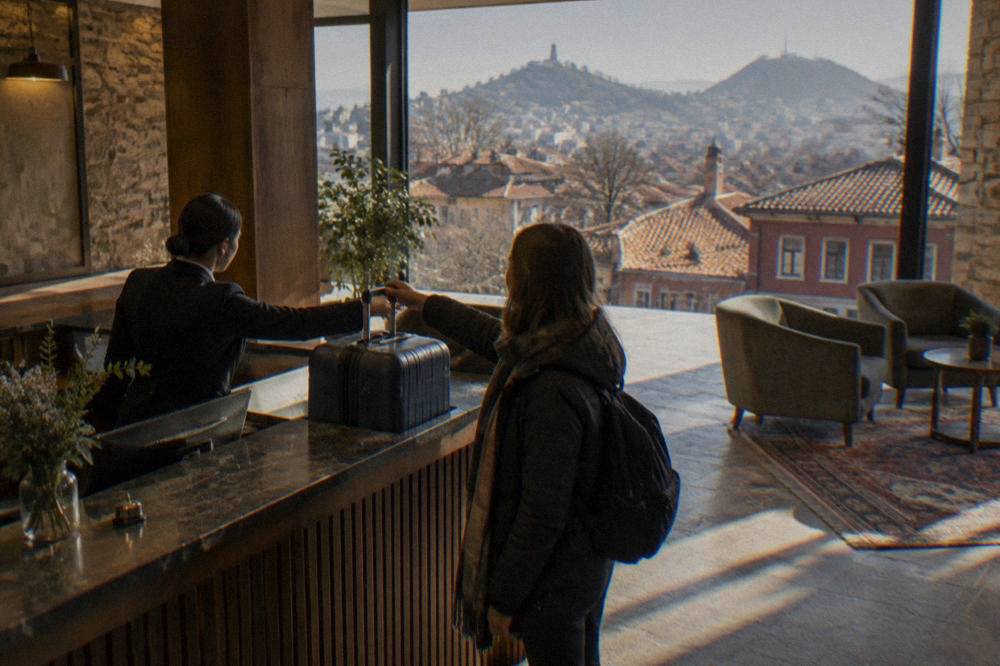Traveller handing a suitcase across a hotel reception desk in Plovdiv