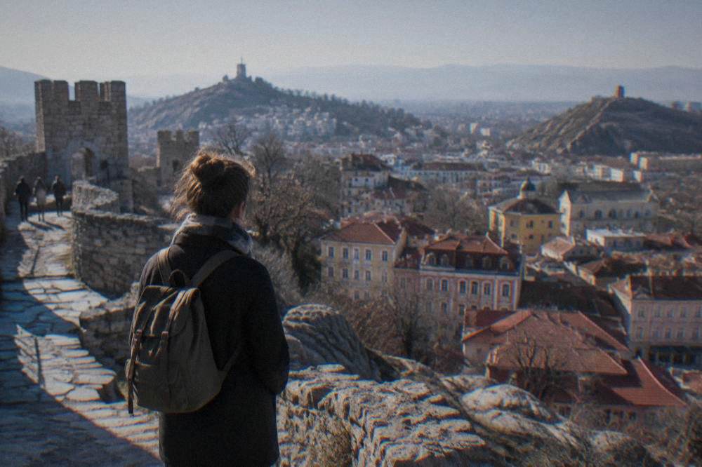 Traveller with a small backpack looking out from Nebet Tepe over the city of Plovdiv