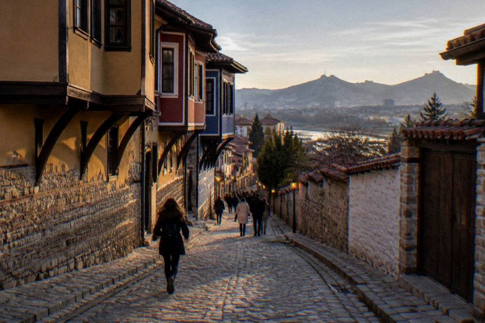 A lit pedestrian shopping street in central Plovdiv with people walking in the evening