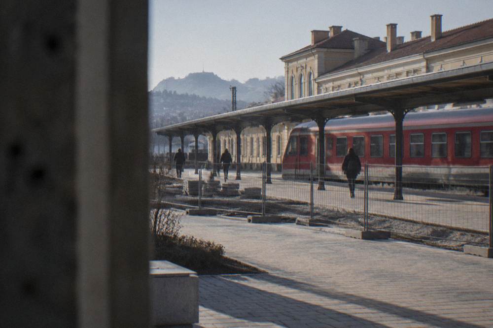 A red regional train standing at a Bulgarian railway station platform