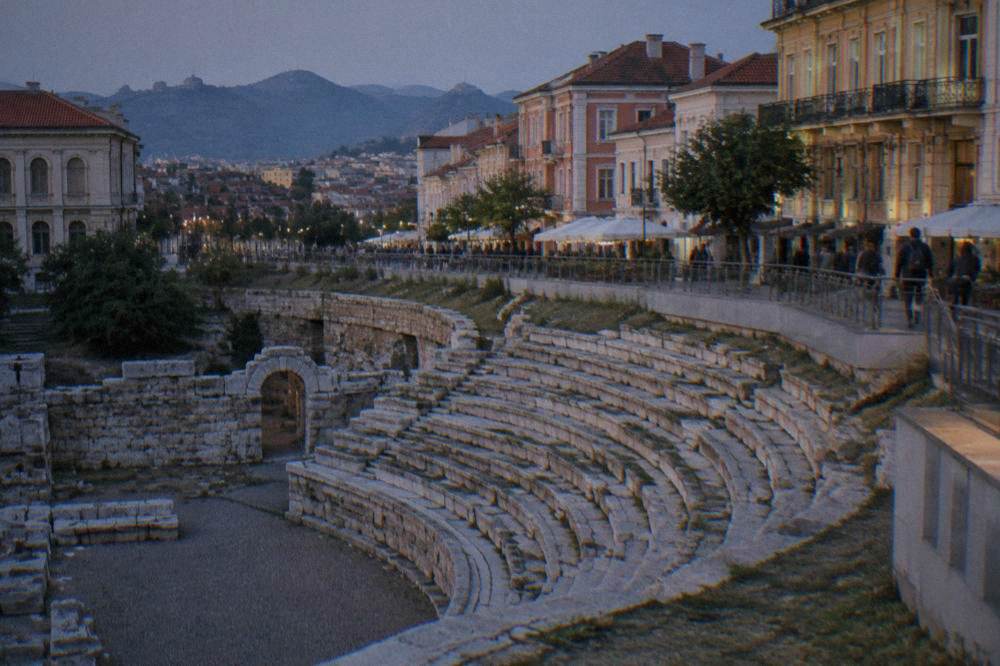 Curved stone seating of an ancient stadium exposed below a modern shopping street