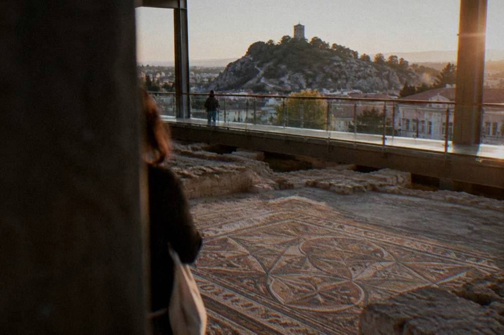Ancient floor mosaics viewed from a raised walkway inside a modern museum hall