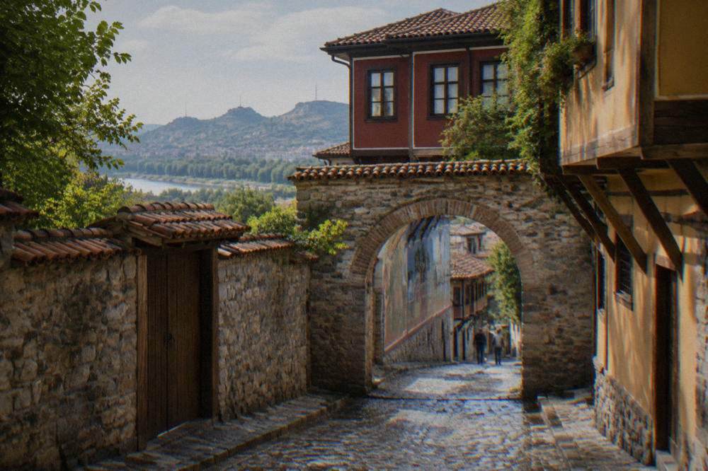 A stone gate in an old town street with painted artwork visible on a wall beyond it