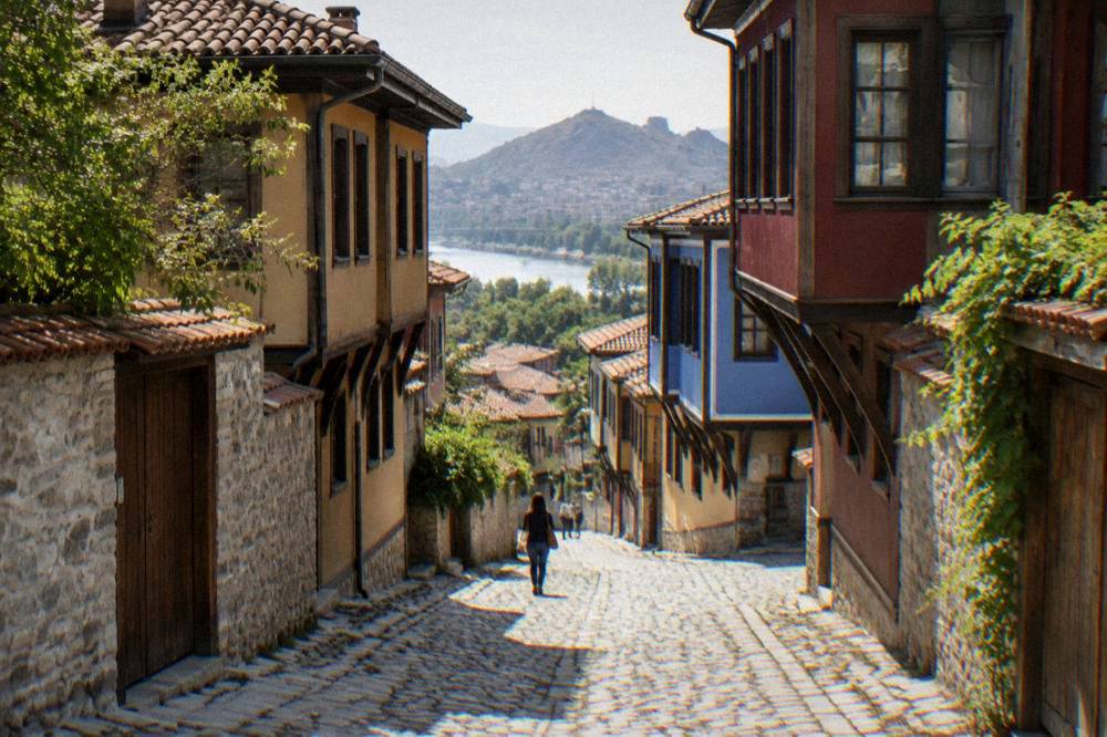 Sunlit cobbled street with colourful revival era houses in an old town