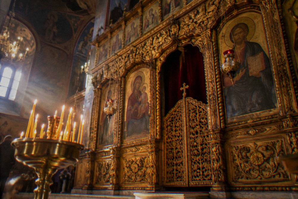 Ornate interior of an Orthodox church with iconostasis and candles
