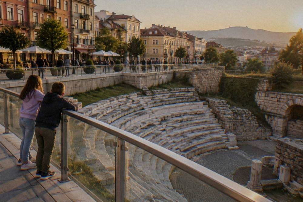 Children looking at the Roman Stadium sphendone below the pedestrian Main Street in Plovdiv