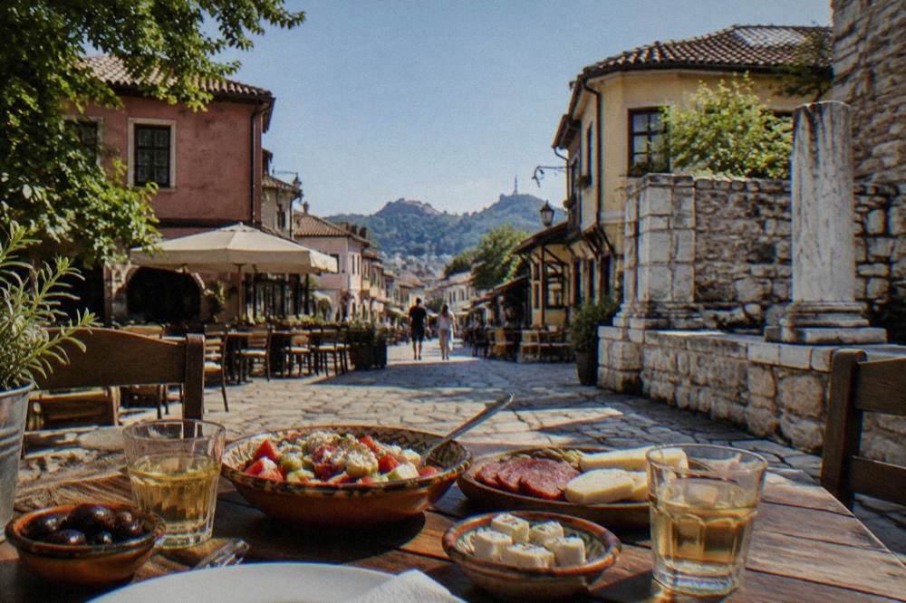 A Bulgarian meze spread with shopska salad, cheese, cured meat and two glasses of rakia
