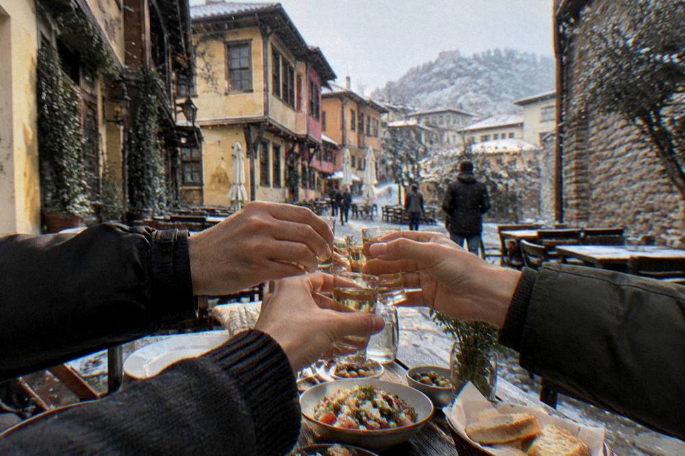 Friends raising small glasses of rakia in a toast around a restaurant table