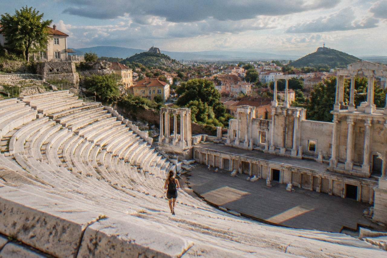 Marble seating rows of an ancient Roman theatre on a hillside above red rooftops