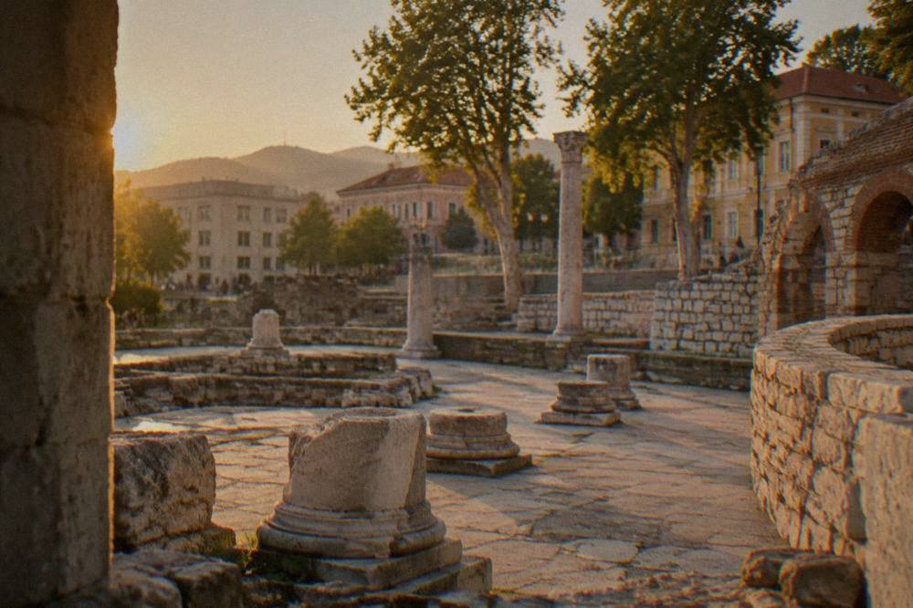 Stone arches and curved ruin walls beside a modern city square