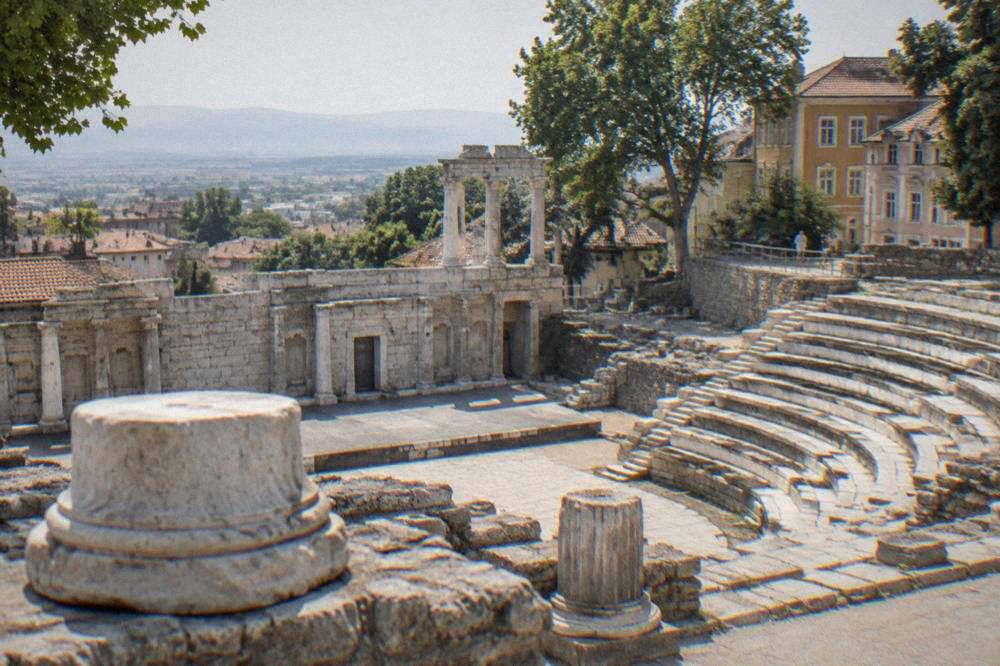 A semicircle of stone tiers facing a stage wall under an open sky