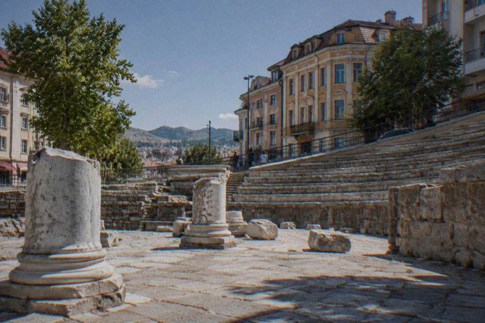 Curved stone tiers enclosed by modern buildings on a busy street corner