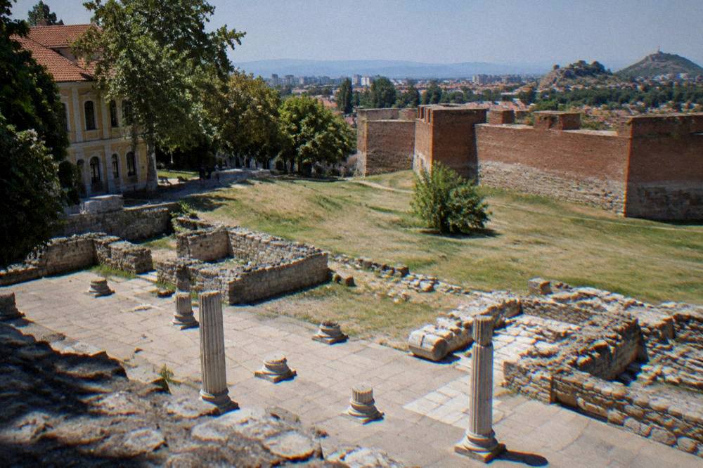 Red brick fortress walls of an ancient Roman town standing in a grassy field