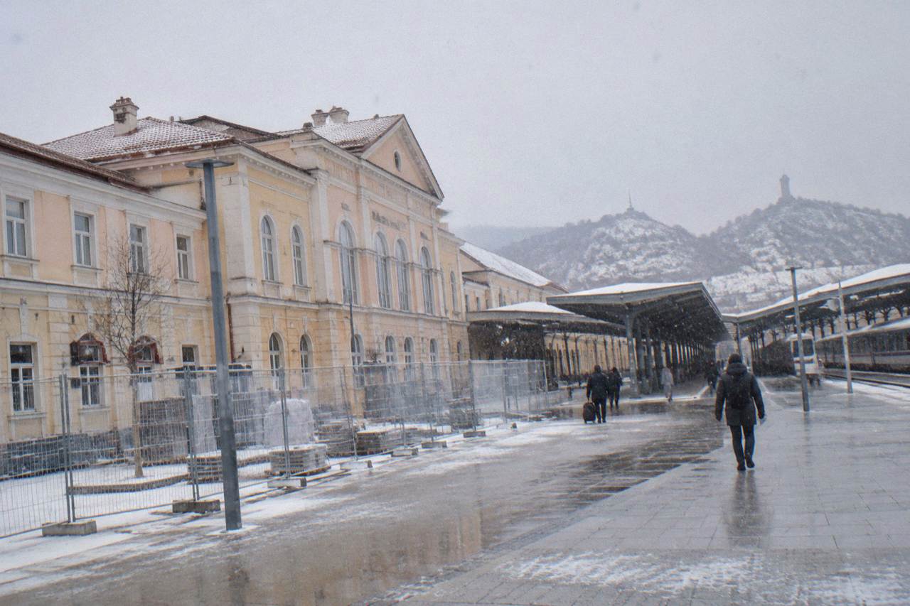 A red BDZ passenger train standing at a railway platform in Bulgaria