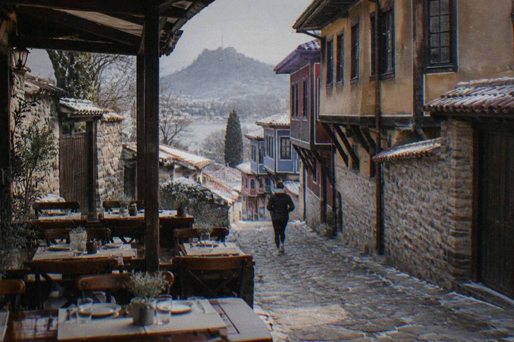 A shaded restaurant terrace with tables set for lunch in a Bulgarian old town