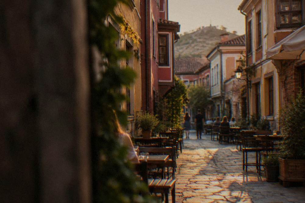 Narrow Kapana street with small tables outside colorful storefronts in the evening