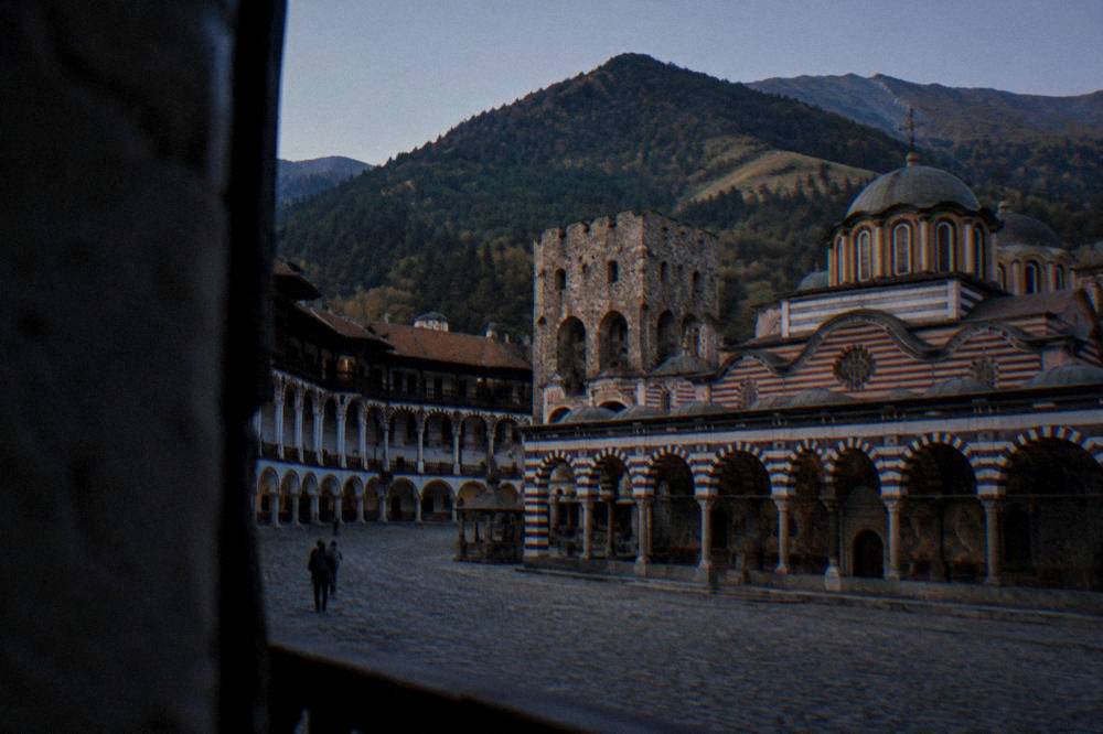 Rila Monastery seen across its courtyard with striped arcades and the mountains behind