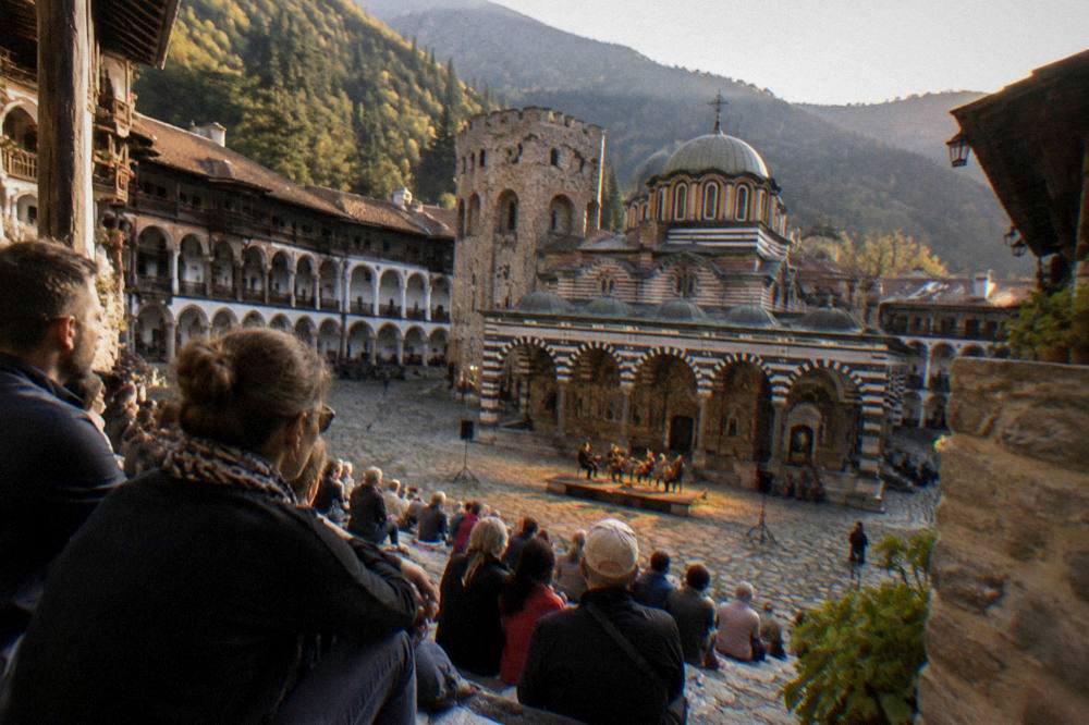 Evening concert audience in an ancient stone theatre under warm light