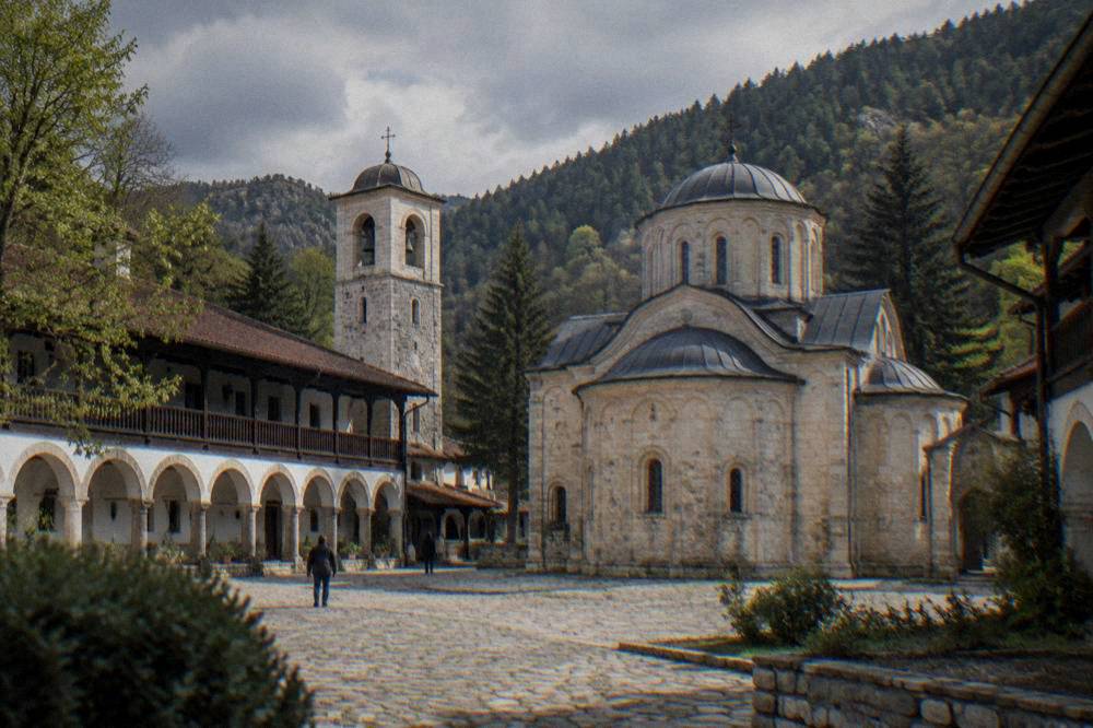 The courtyard of Bachkovo Monastery under grey skies, arched walkways offering cover along the walls