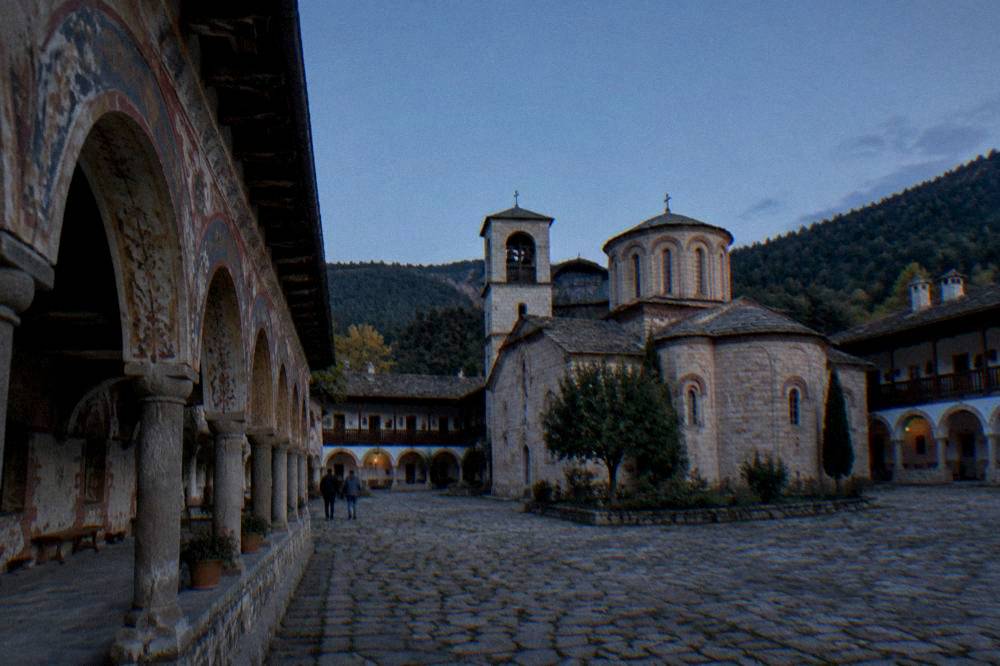 Arcaded stone cloister of Bachkovo Monastery with colourful frescoes on the walls
