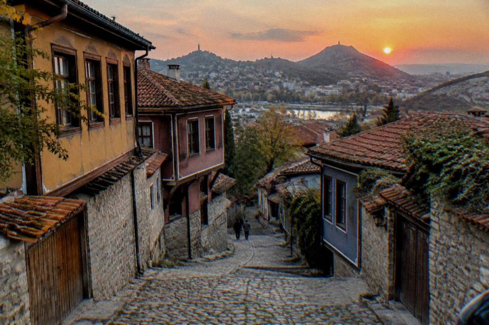 Sunset over the rooftops of Plovdiv with the hills silhouetted against an orange sky