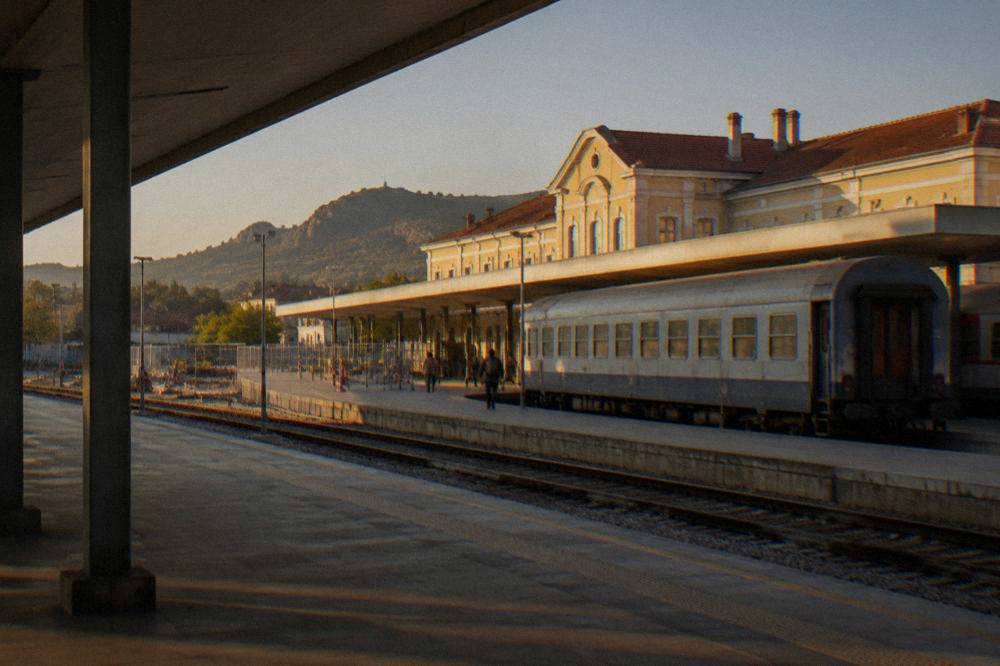 A passenger train standing at a Bulgarian railway station platform under a clear sky