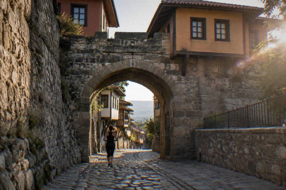A stone gate of Hisar Kapia with old houses rising above it in Plovdiv Old Town