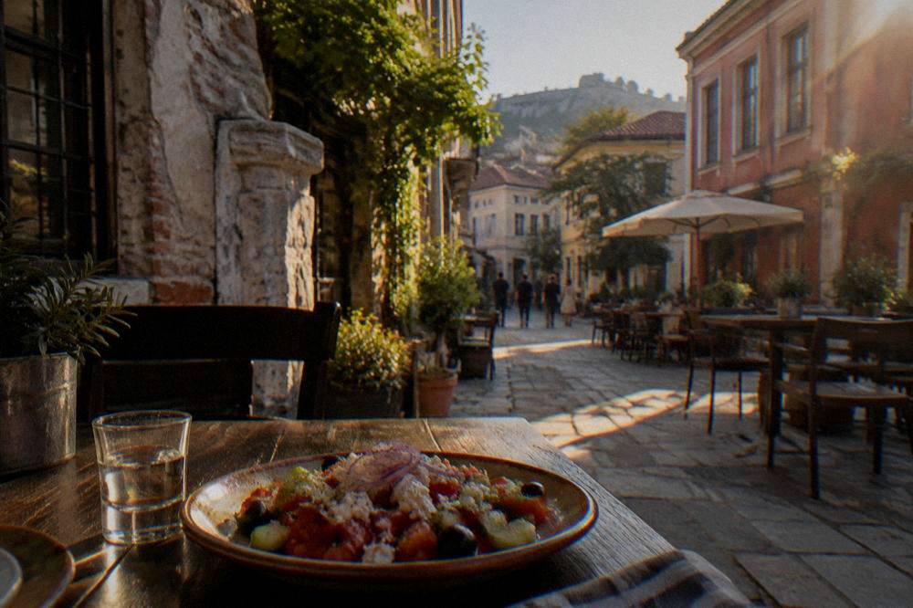 A small glass of rakia beside a plate of shopska salad on a restaurant table