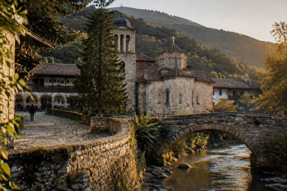 A stone arched bridge over a river in a Rhodope village at golden hour.